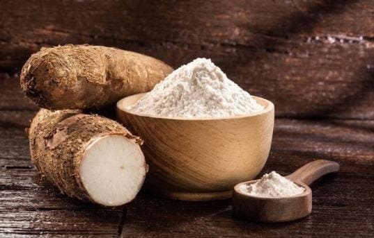 Almidón de yuca y raíces de yuca sobre madera