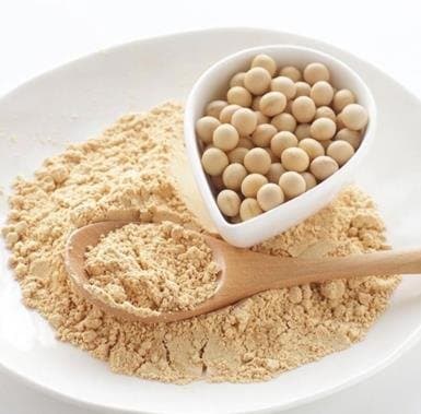Harina de soya en una cuchara sobre granos de soya