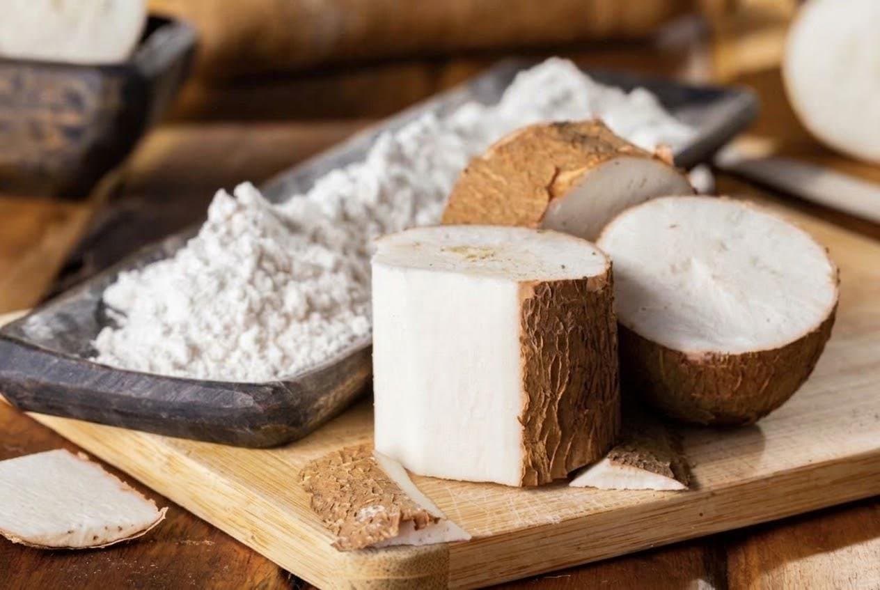 Harina de yuca y trozos de yuca pelada sobre una tabla